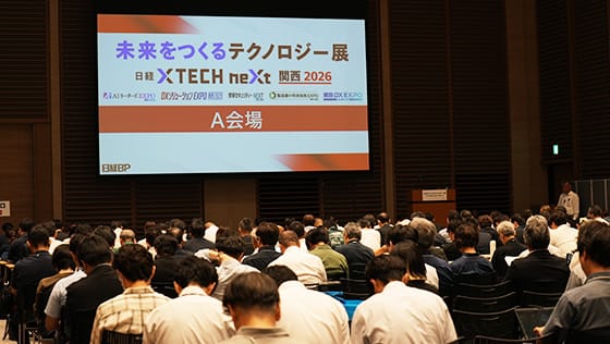 大型スクリーンに「未来をつくるテクノロジー展 日経XTECH next 関西2026 A会場」と表示された会場で、来場者が着席している様子