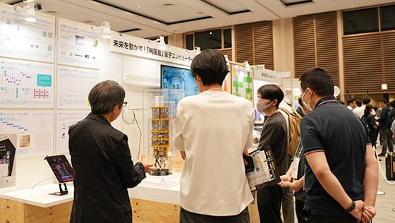 展示ブースの前で来場者がスタッフの説明を聞いている様子